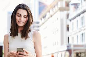 A smiling woman is looking down at her phone